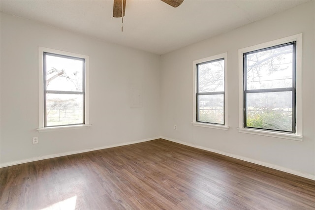 unfurnished room with baseboards, dark wood-style flooring, ceiling fan, and plenty of natural light