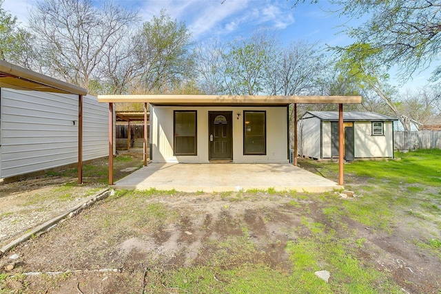 back of house featuring fence, a storage shed, an outdoor structure, and a patio area