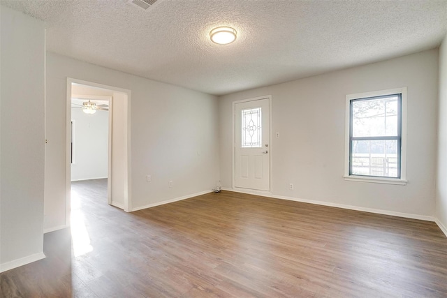unfurnished room with baseboards, wood finished floors, and a textured ceiling