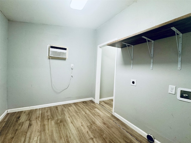 clothes washing area featuring laundry area, wood finished floors, baseboards, and an AC wall unit