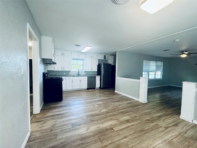 kitchen featuring white cabinets, a sink, open floor plan, light wood-style floors, and black appliances