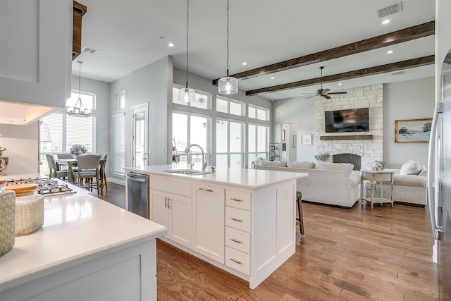 kitchen featuring visible vents, a sink, appliances with stainless steel finishes, a fireplace, and ceiling fan with notable chandelier