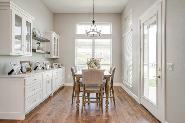 dining room with baseboards, an inviting chandelier, and wood finished floors