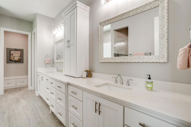 full bath with a sink, a shower, double vanity, and wood finished floors