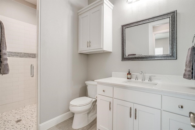 bathroom with a shower stall, vanity, baseboards, and toilet