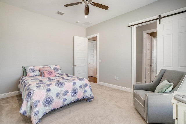 bedroom featuring light colored carpet, baseboards, visible vents, and a barn door