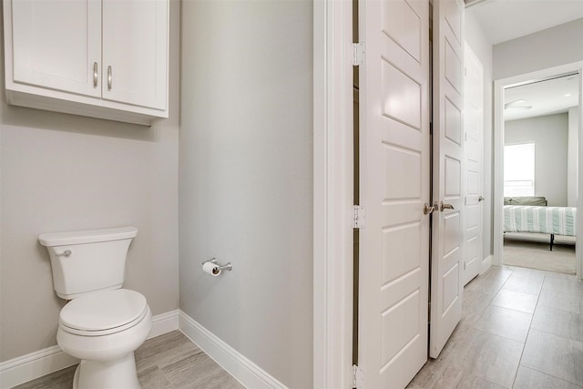 bathroom featuring toilet, baseboards, and connected bathroom