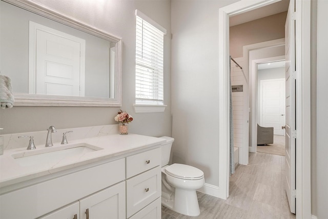 bathroom featuring toilet, a closet, vanity, and baseboards