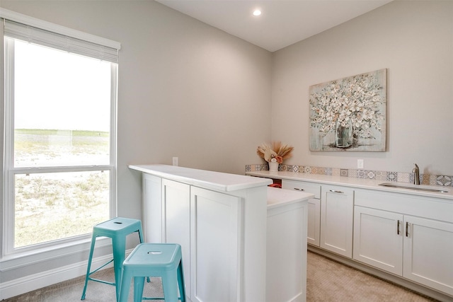 laundry room with light colored carpet, a sink, baseboards, and recessed lighting