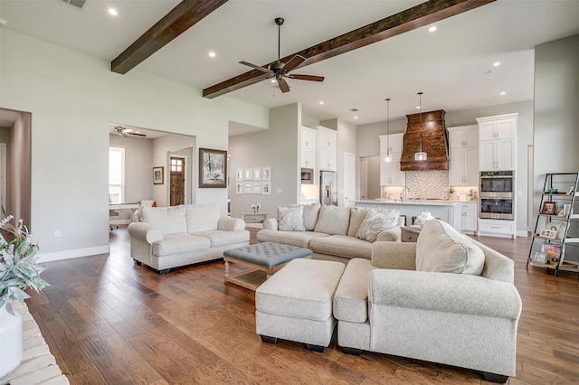 living area featuring beamed ceiling, dark wood-type flooring, baseboards, and a ceiling fan