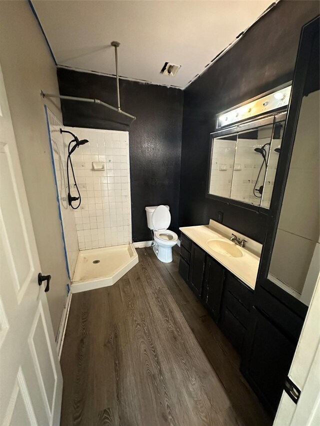 301 E White St, Pilot Point, TX 76258 - bathroom with wood finished floors, a tile shower, vanity, and toilet