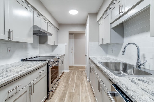 6050 Birchbrook Dr Unit 142, Dallas, TX 75206 - kitchen featuring extractor fan, a sink, stainless steel appliances, light wood finished floors, and backsplash