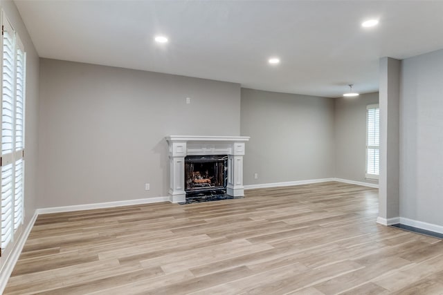 6050 Birchbrook Dr Unit 142, Dallas, TX 75206 - unfurnished living room featuring light wood-type flooring, baseboards, recessed lighting, and a fireplace with flush hearth