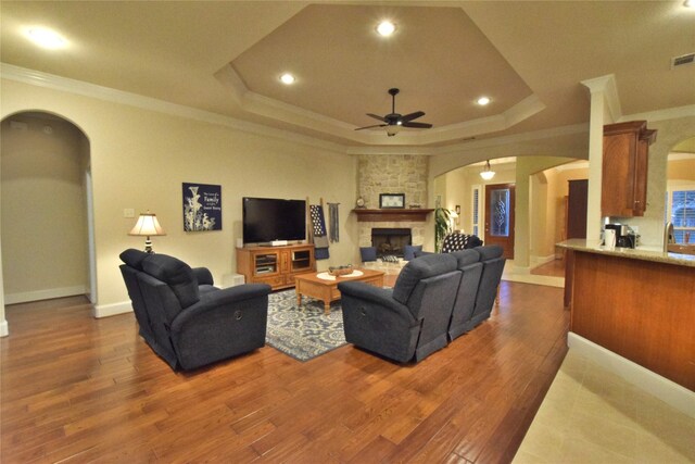 13111 Saint Orlin Way, Talty, TX 75126 - living room featuring arched walkways, a ceiling fan, ornamental molding, a fireplace, and a tray ceiling
