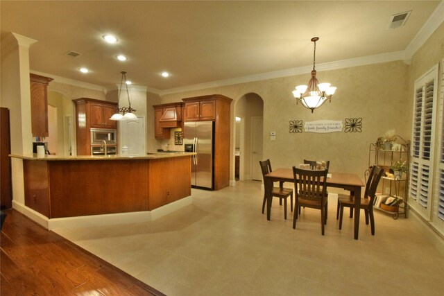 13111 Saint Orlin Way, Talty, TX 75126 - kitchen with stainless steel appliances, ornamental molding, brown cabinetry, arched walkways, and a chandelier