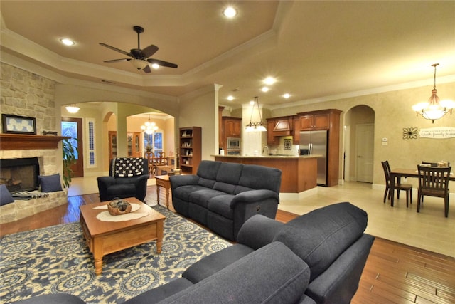 13111 Saint Orlin Way, Talty, TX 75126 - living room with a chandelier, arched walkways, ornamental molding, a tray ceiling, and light wood-style floors