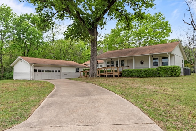 single story home featuring cooling unit, an outbuilding, concrete driveway, a front yard, and a porch