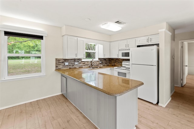 kitchen featuring tasteful backsplash, white appliances, a sink, visible vents, and a peninsula