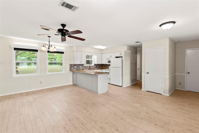 kitchen featuring light wood-style flooring, a peninsula, white appliances, ceiling fan, and tasteful backsplash