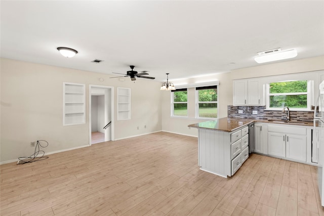 kitchen featuring a sink, a peninsula, plenty of natural light, visible vents, and light wood-style floors