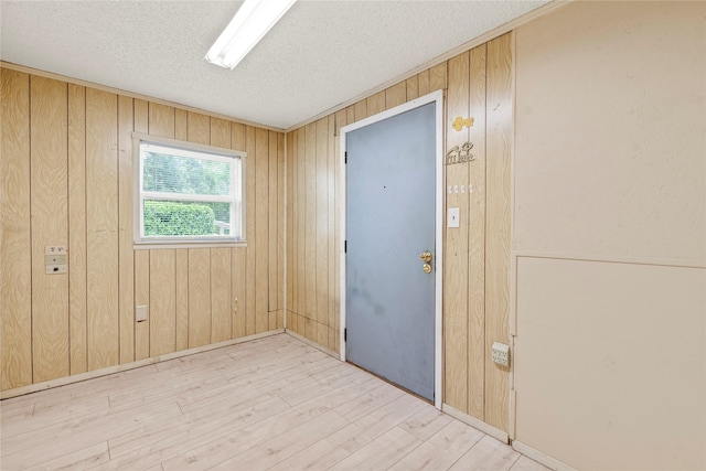 empty room with a textured ceiling, wood finished floors, and wooden walls