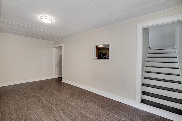 basement featuring baseboards, freestanding refrigerator, stairway, and dark wood finished floors
