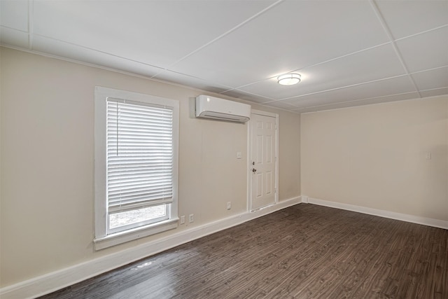 spare room featuring baseboards, a wall mounted AC, and dark wood finished floors
