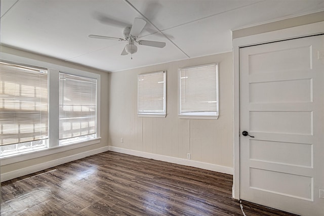 spare room with dark wood-type flooring, ceiling fan, and baseboards