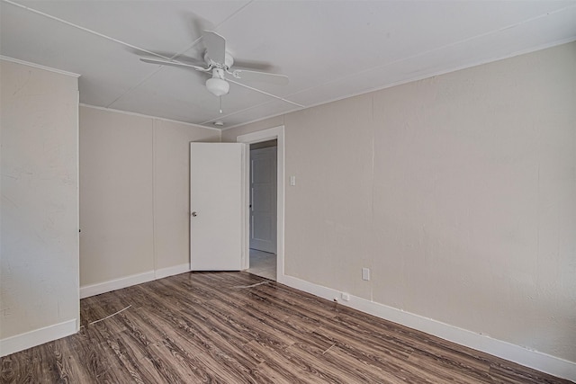 empty room featuring a ceiling fan, ornamental molding, baseboards, and wood finished floors