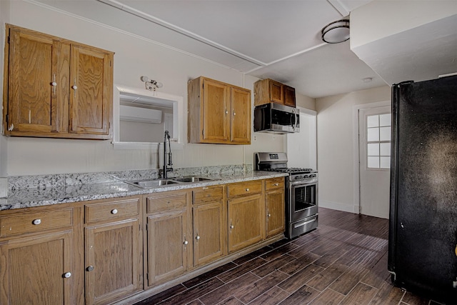 kitchen with wood finish floors, stainless steel appliances, an AC wall unit, a sink, and brown cabinetry