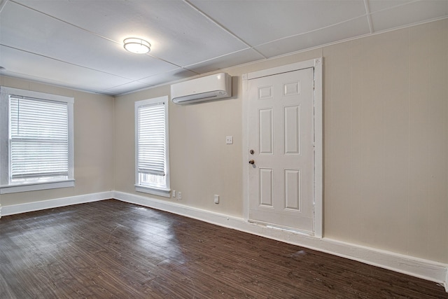 unfurnished room with dark wood finished floors, baseboards, and a wall mounted AC