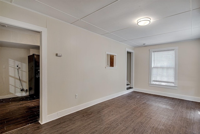 empty room featuring baseboards and dark wood finished floors
