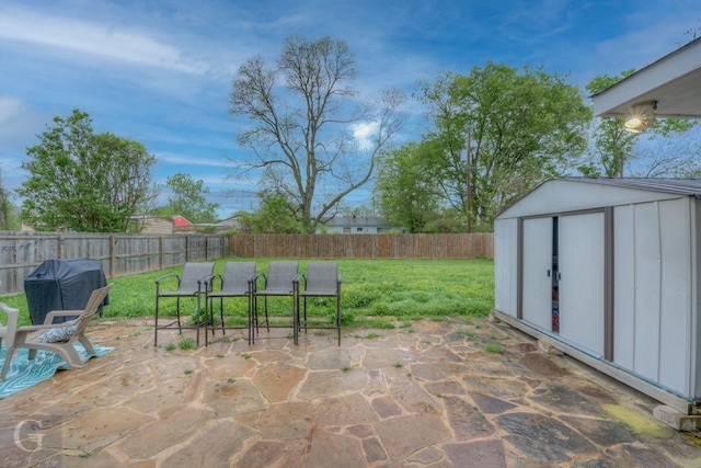 view of patio / terrace with a fenced backyard, grilling area, an outbuilding, and a storage unit