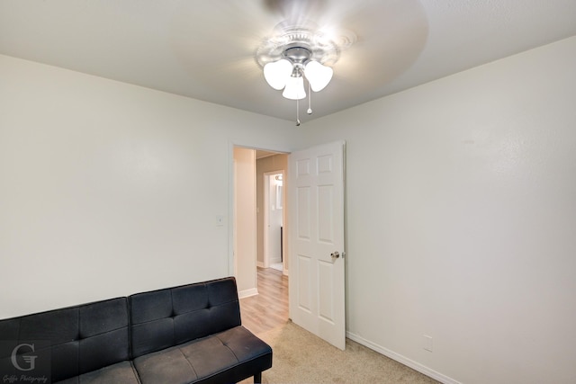 living area with light colored carpet, ceiling fan, and baseboards