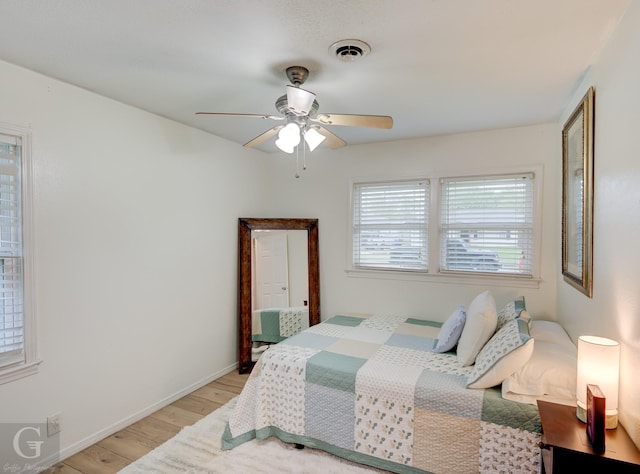 bedroom with baseboards, light wood-style floors, ceiling fan, and visible vents