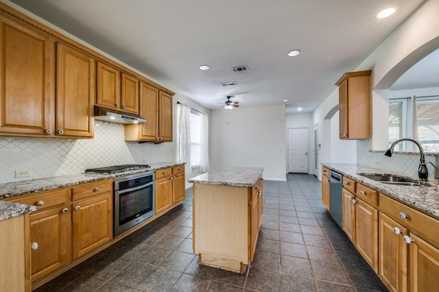 kitchen featuring under cabinet range hood, a sink, arched walkways, a ceiling fan, and appliances with stainless steel finishes