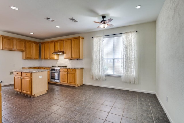 kitchen featuring light stone countertops, stove, baseboards, visible vents, and ceiling fan