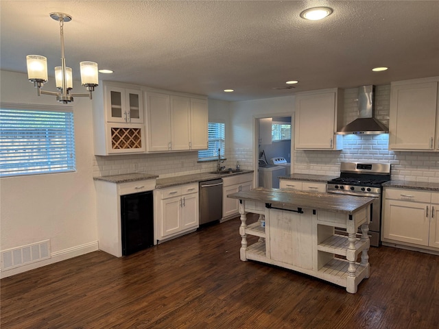 10388 Sandra Lynn Dr, Dallas, TX 75228 - kitchen featuring wall chimney exhaust hood, stainless steel appliances, open shelves, a sink, and independent washer and dryer