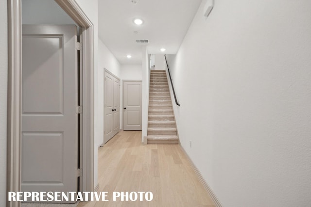 hallway featuring light wood-type flooring, baseboards, recessed lighting, stairs, and visible vents