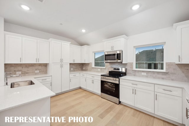 kitchen featuring a sink, tasteful backsplash, white cabinets, and appliances with stainless steel finishes