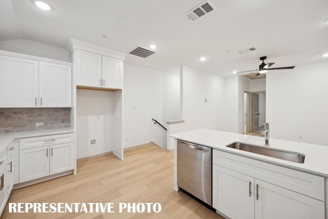 kitchen featuring stainless steel dishwasher, tasteful backsplash, white cabinets, visible vents, and a sink