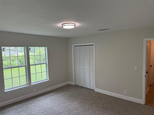 unfurnished bedroom featuring carpet floors, visible vents, baseboards, and multiple windows