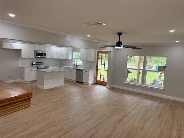 kitchen with stainless steel appliances, visible vents, a sink, crown molding, and open floor plan