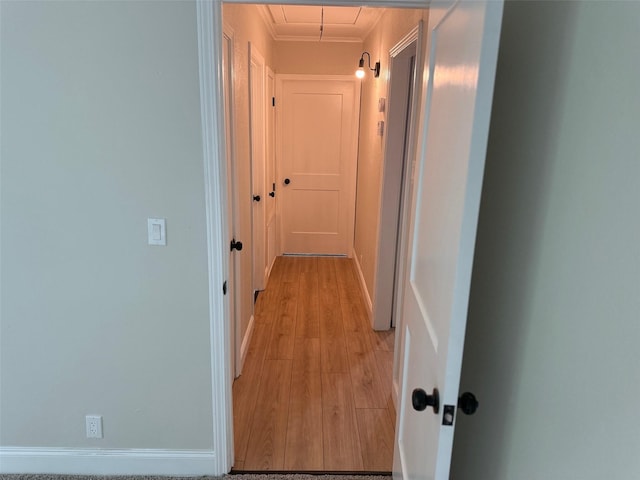 corridor with light wood-type flooring, attic access, and crown molding
