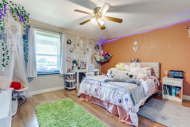 bedroom featuring ceiling fan, baseboards, ornamental molding, and wood finished floors