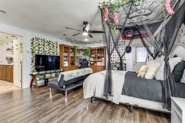 bedroom with visible vents, crown molding, and wood finished floors