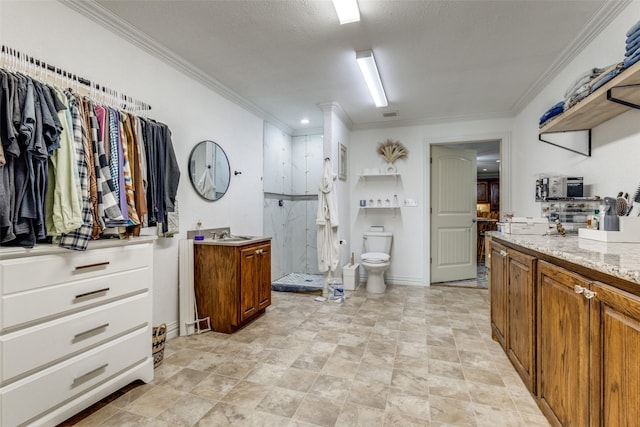 interior space featuring toilet, a marble finish shower, ornamental molding, and vanity