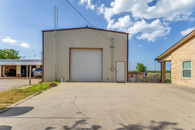 detached garage featuring concrete driveway and fence