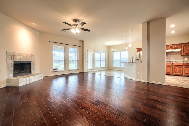 2760 Stoney Hollow Ln, Rockwall, TX 75087 - unfurnished living room featuring a ceiling fan, hardwood / wood-style flooring, a fireplace with raised hearth, a chandelier, and baseboards