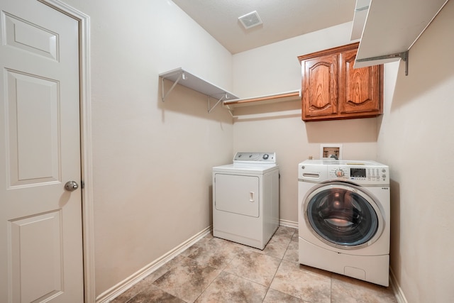 clothes washing area featuring washer and clothes dryer, cabinet space, baseboards, and light tile patterned floors